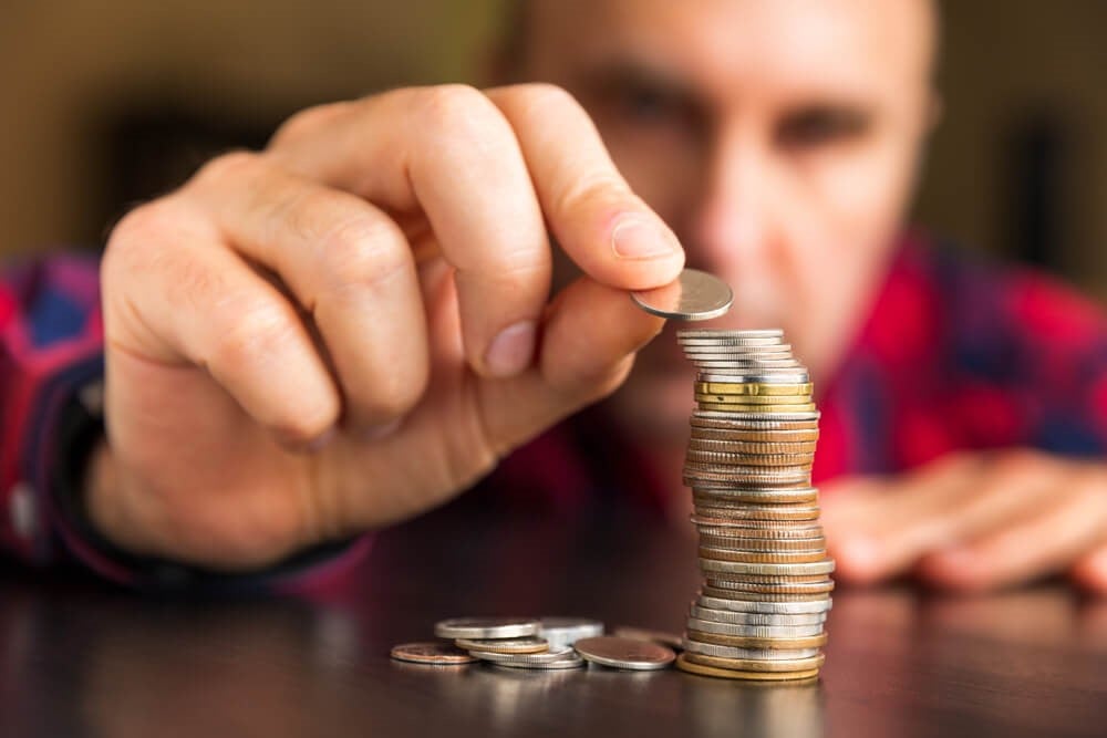 A man piling coins onto each other to save.